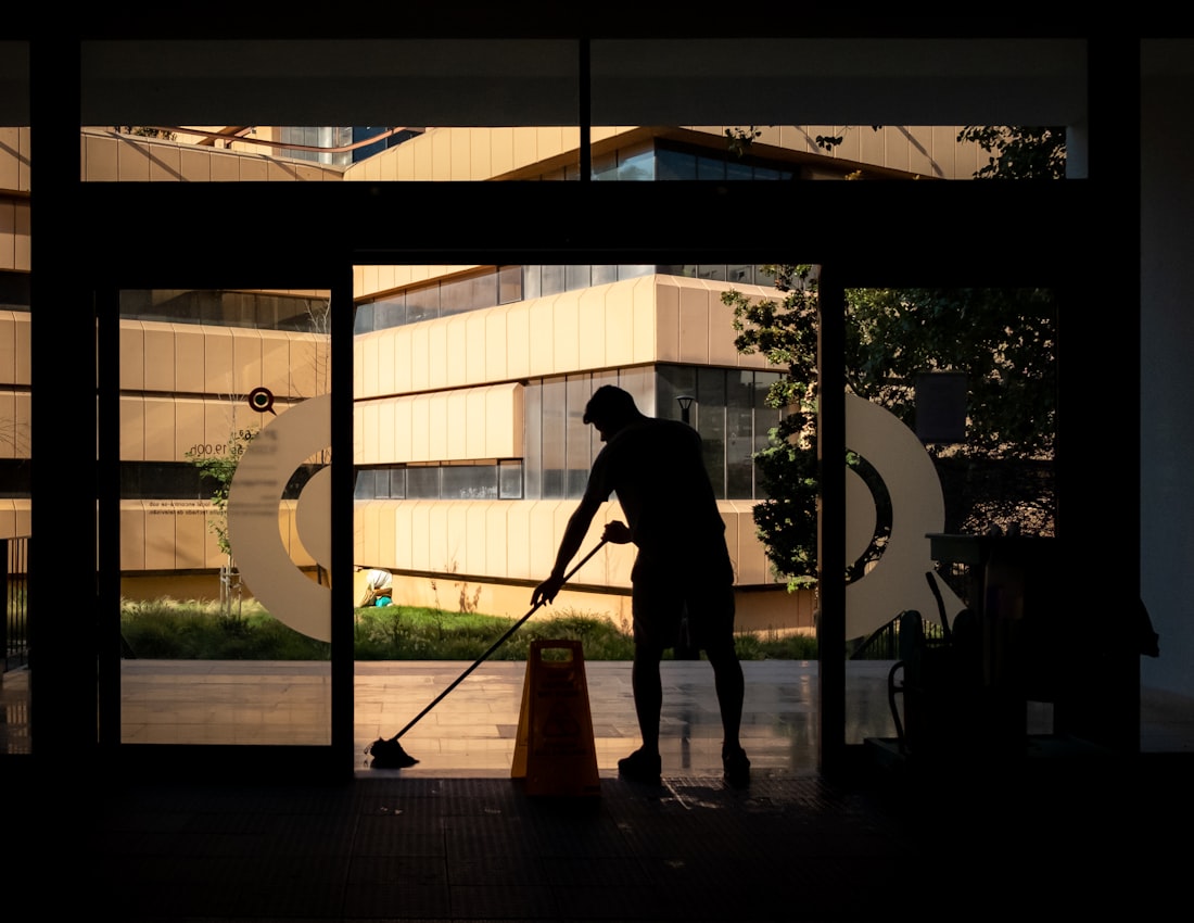 Professional janitorial technician cleaning a commercial building entrance