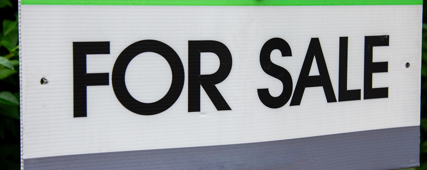 Real estate for sale sign in front of a property listed on the market